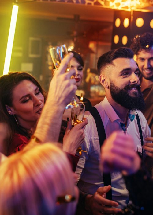 Group of energetic young people dancing at a party in a nightclub